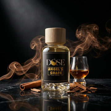 Bottle of Dose Angel's Share with a glass of whiskey and cinnamon sticks on a dark background